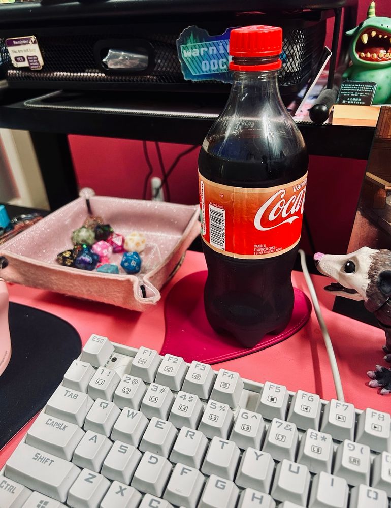 A picture of Judy’s setup for her game. A Vanilla Coke, a pink tray of dice, and several little monster figurines.