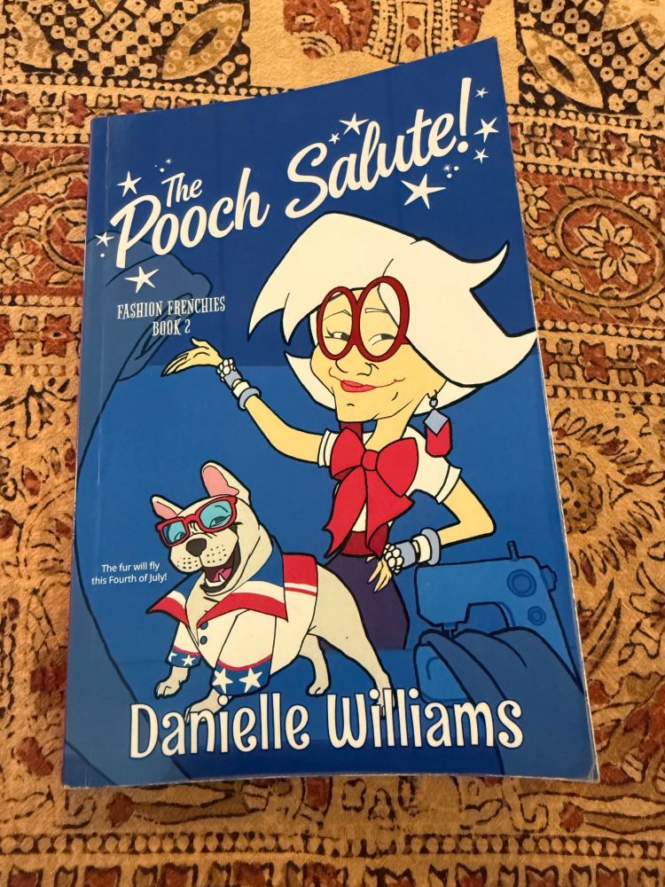 A copy of the book, The Pooch Salute by Danielle Williams, lying on a table