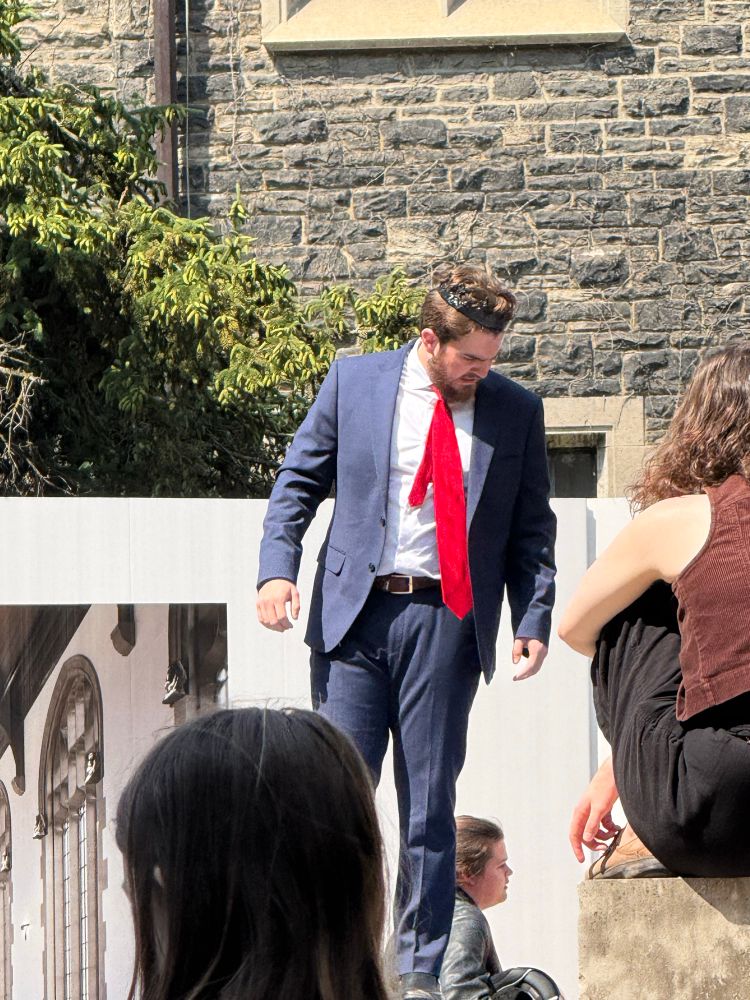 Herod, in a blue suit with an overly long red tie, orders the slaughter of the innocents. From the York mystery plays 2025 at the University of Toronto 