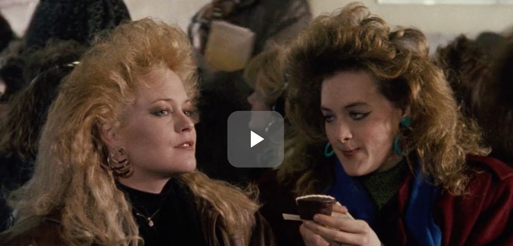 Screenshot of Melanie Griffith and Joan Cuasck with enormous, teased and curled, 1980s hair. No seriously, think hair metal bands and then add even more volume. It's glorious.