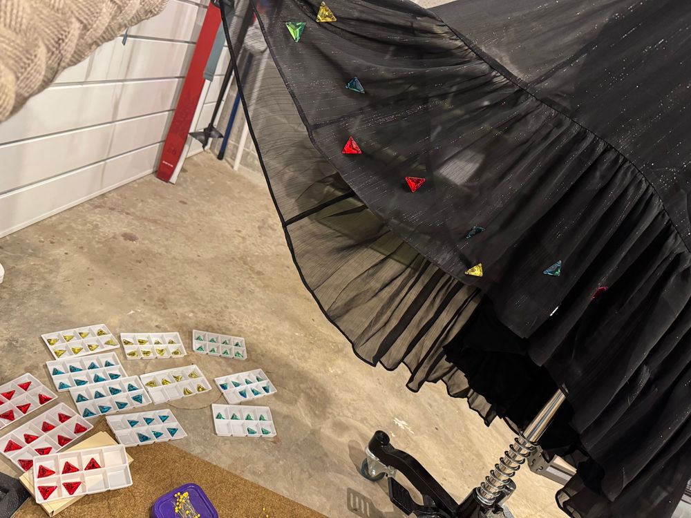 Wip photo of rhinestones being sewn on a black dress