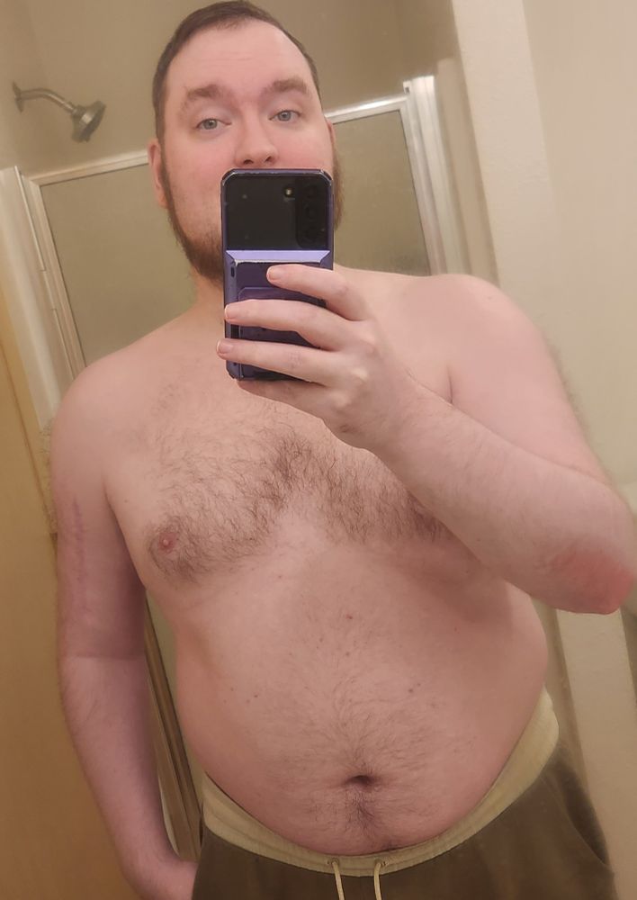 A gay looking very high while looking into the mirror for a shirtless mirror selfie