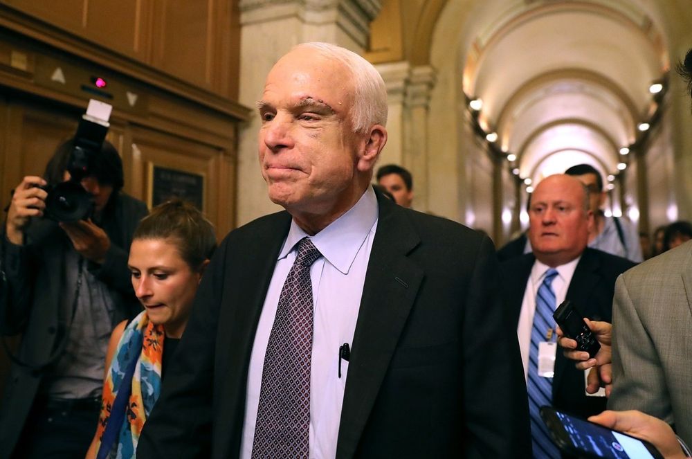 Former Senator John McCain is surrounded by reporters.