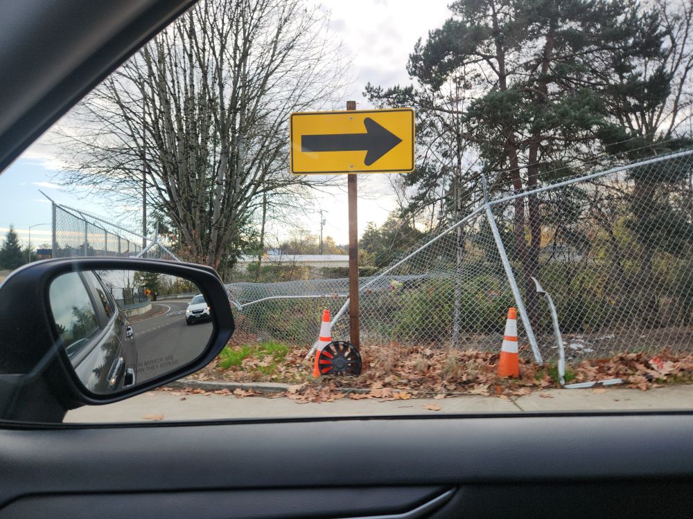 Damaged fence with right pointing arrow sign.