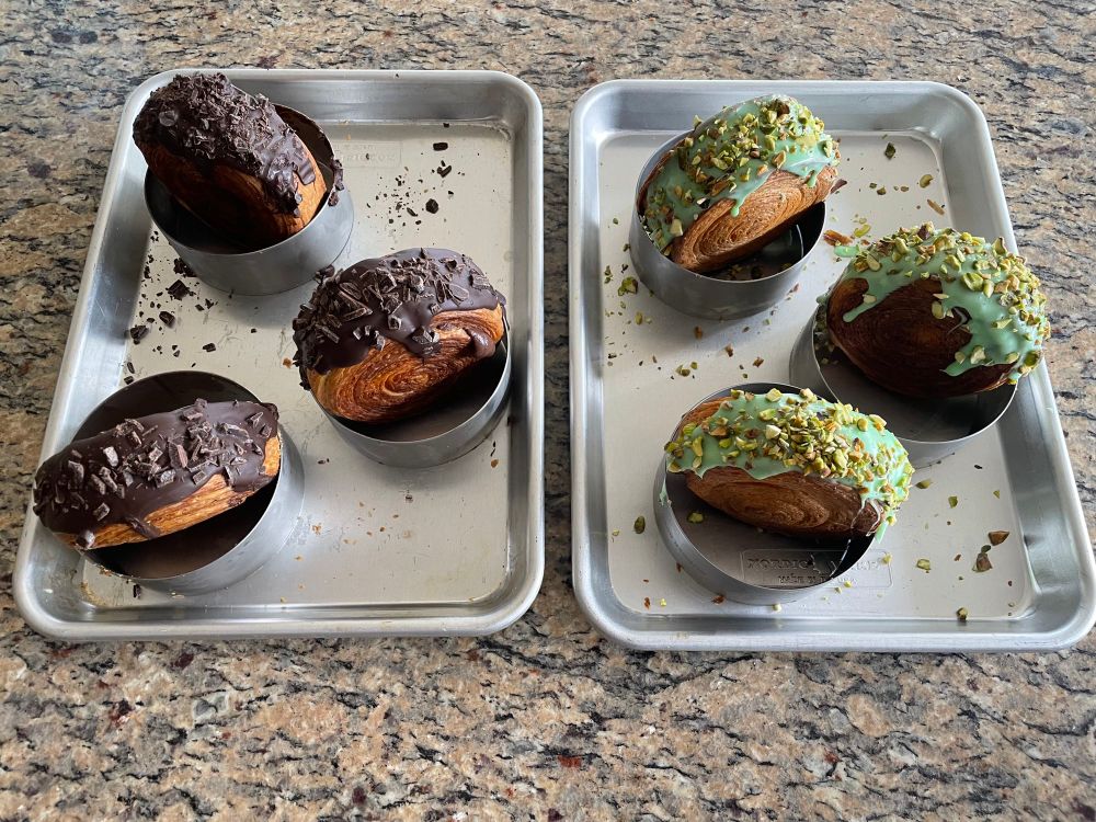Supreme croissants resting on their baking rings.
