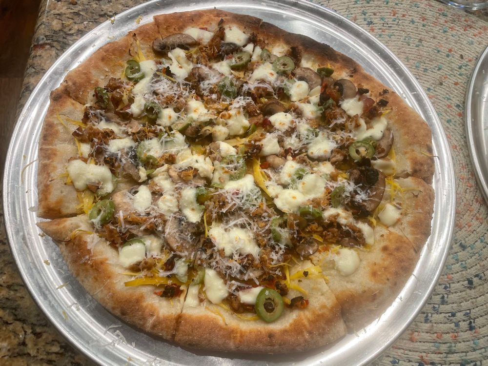 Pizza with mushrooms, mozzarella, olives, and Romano cheese.
