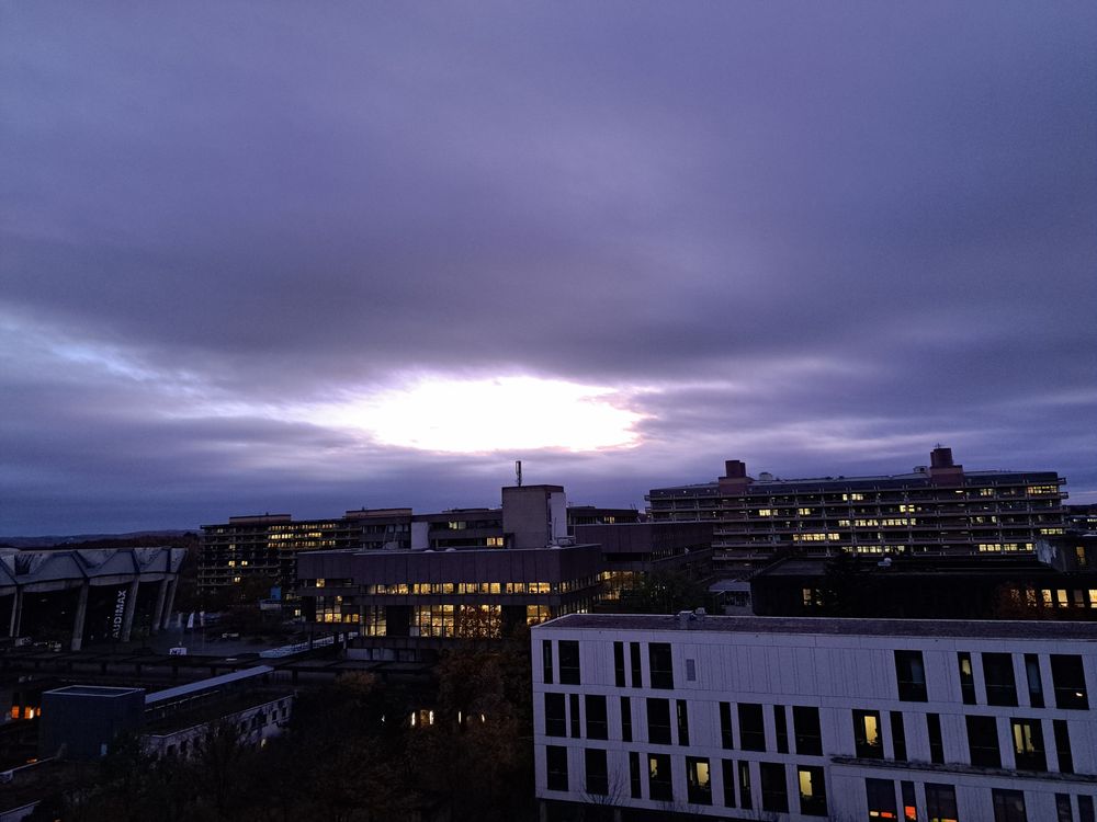 Evening sky over university campus, with dark clouds forming a bright hole.