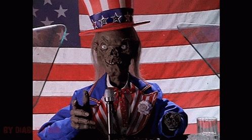 The Crypt Keeper laughing in an ugly patriotic suit