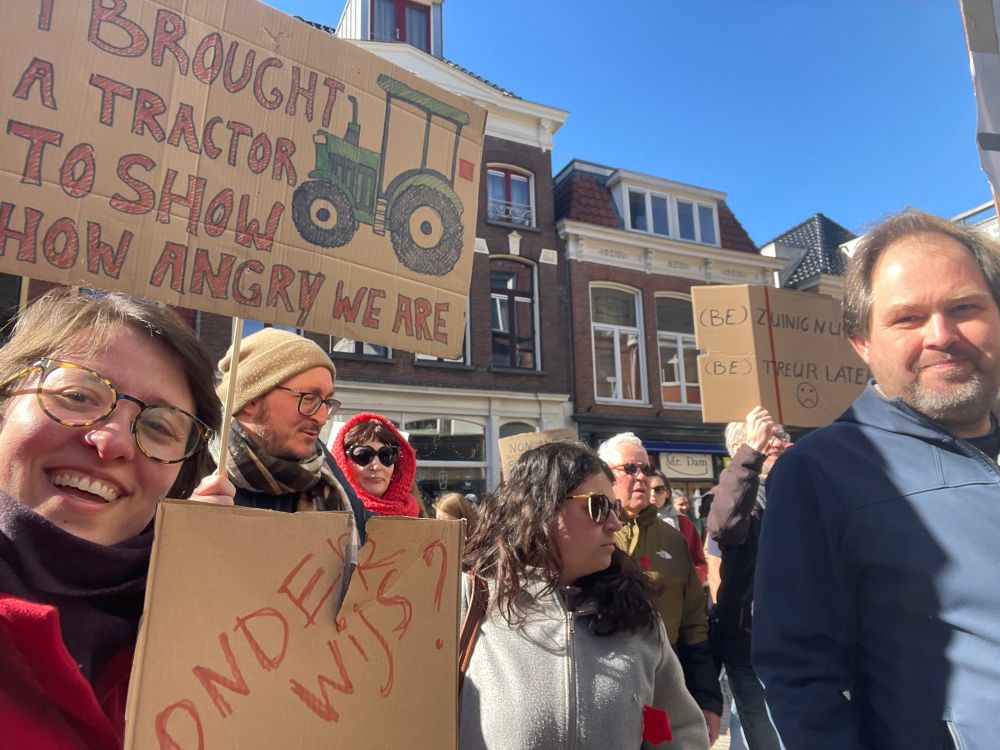 A crowd of protesters in Groningen with signs that say “I brought a tractor to show how angry we are” and a torn sign that says “onderwijs?” To signify the damage the budget cuts would do to education 