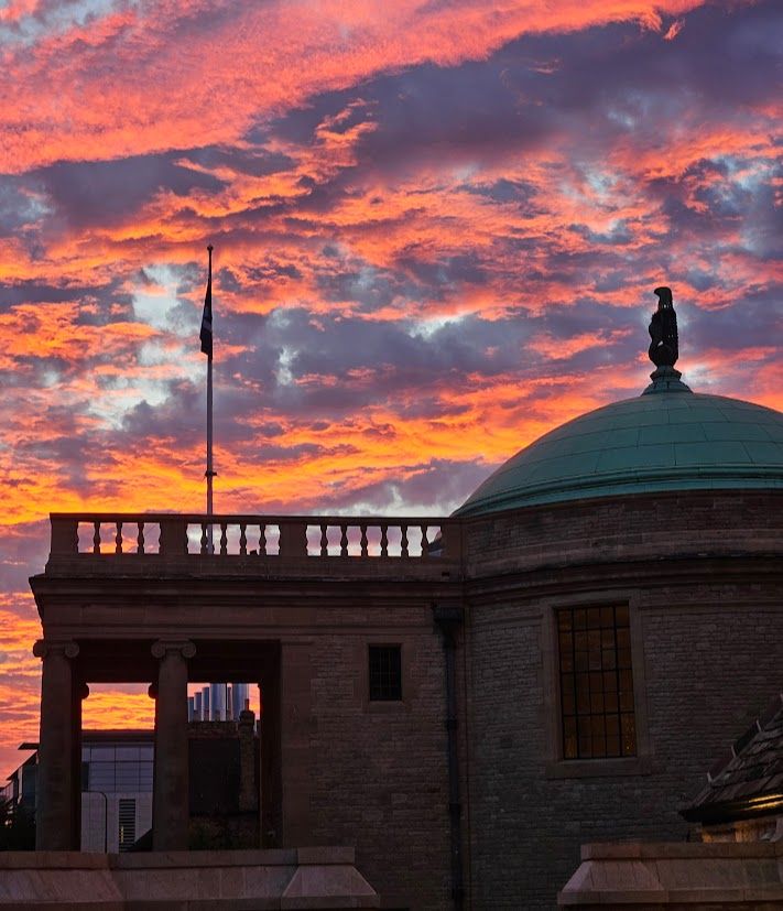 A dramatic orange and purple sunrise behind Rhodes House