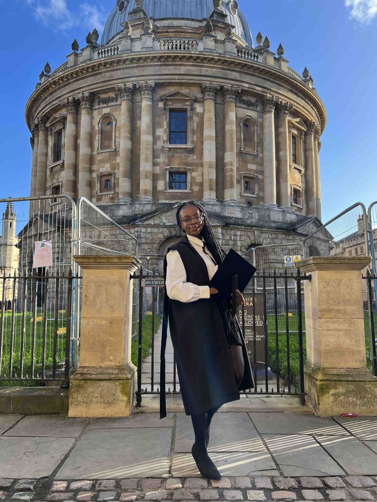 Bertha posing in sub fusc outfit outside the Radcliffe Camera in Oxford