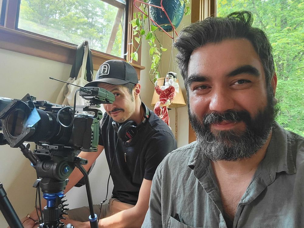Two men sit behind a camera