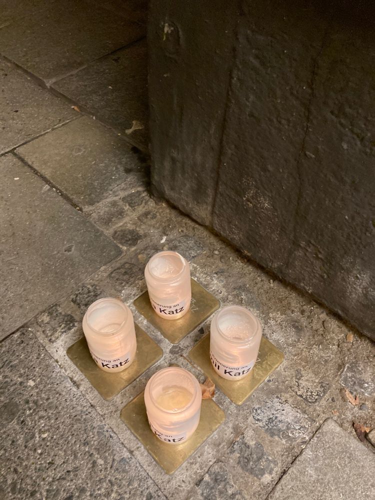 Vier Kerzen stehen auf jeweils einem im Boden eingelassenen Gedenkstein.