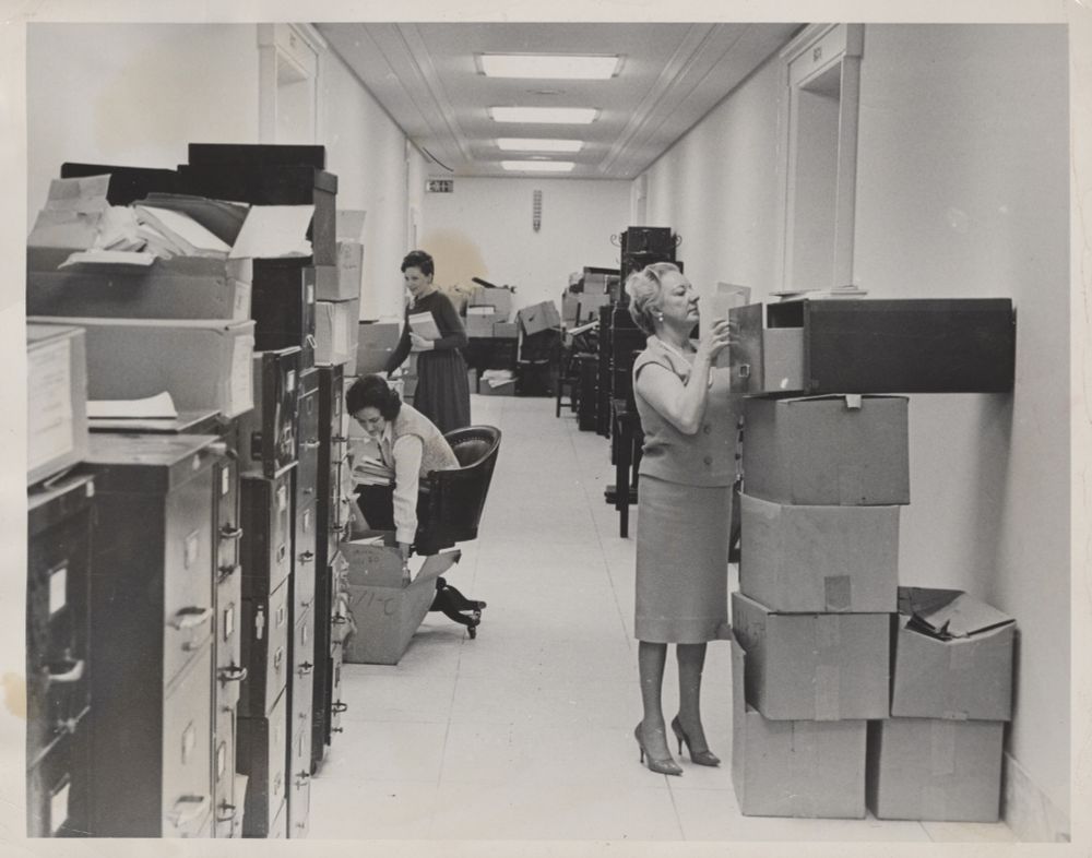 Three women in hallway unpacking boxes