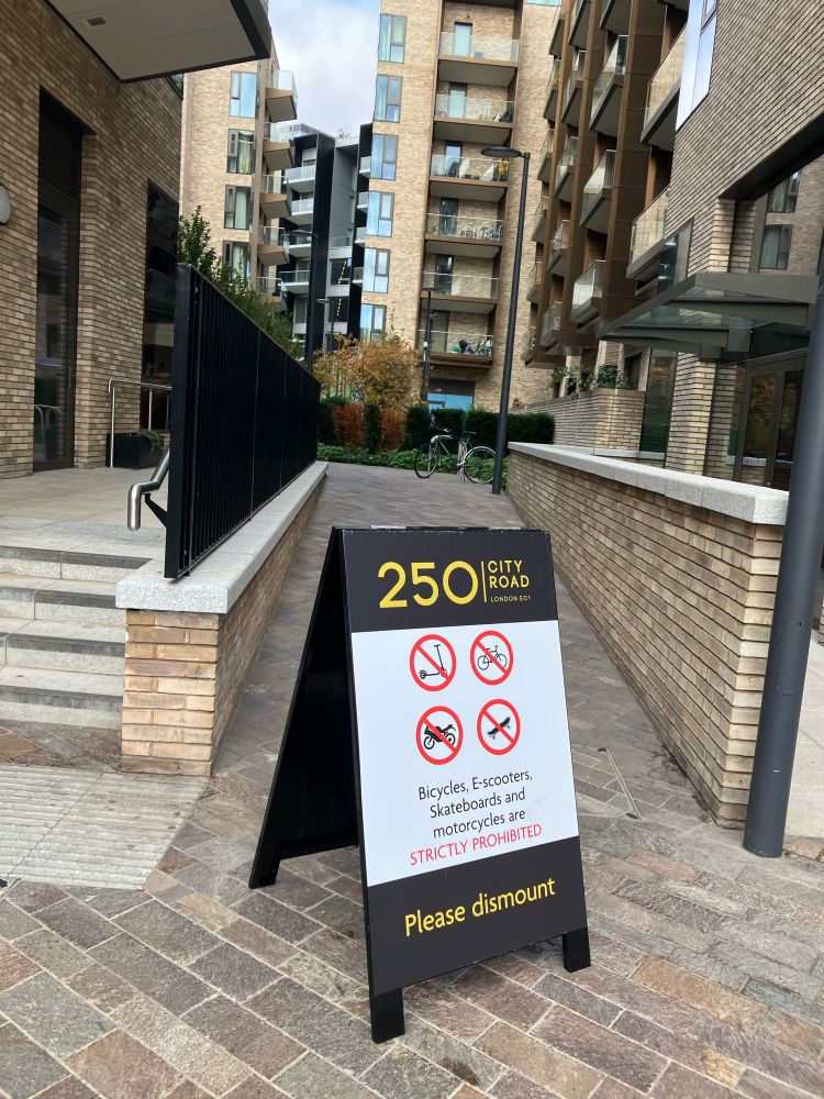A-frame signs blocking access at pinch points details the ban on micro mobility through the estate. It offers a safe and convenient route & there is no good reason for this