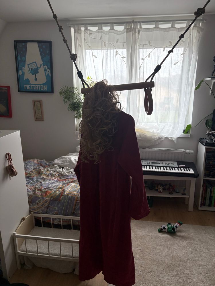 my gymnastic bar that i have in the middle of the room for some reason, a robe and wig are hanging off of it