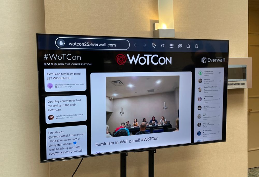 A TV displaying the live feed of WoTCon posts from various social media platforms. 