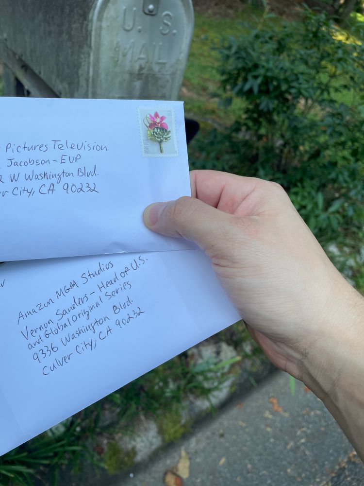 A white hand holding two envelopes. They are addressed to Amazon MGM and Sony Pictures Television. 