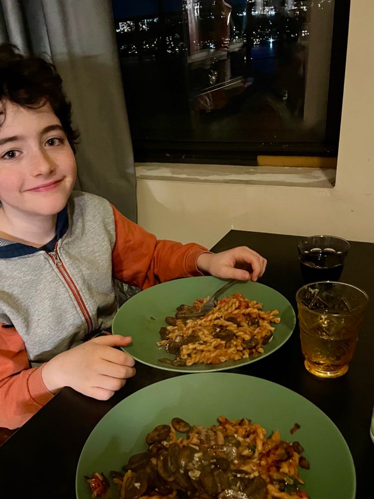 Boy at table with two plates of pasta and drinks