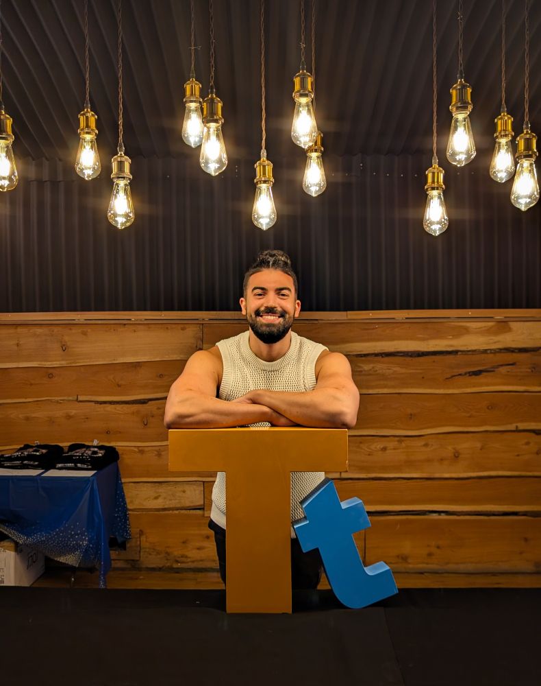 Image of Lewis leaning on a large Tt Games logo sign.