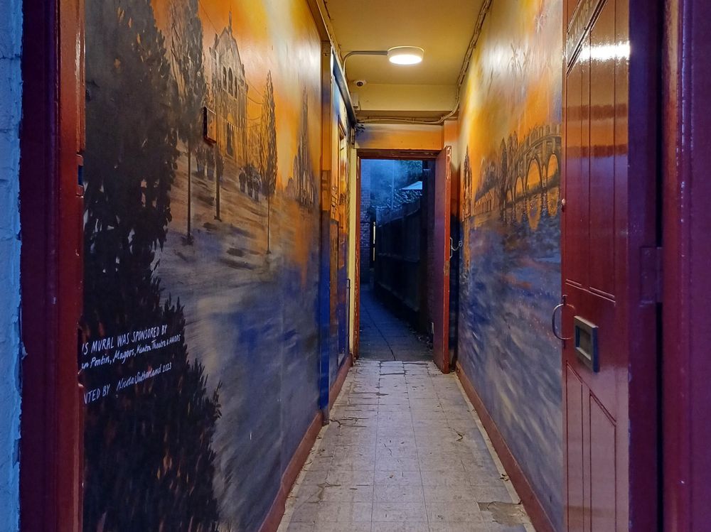 A cool abandoned hallway with murals along the walls