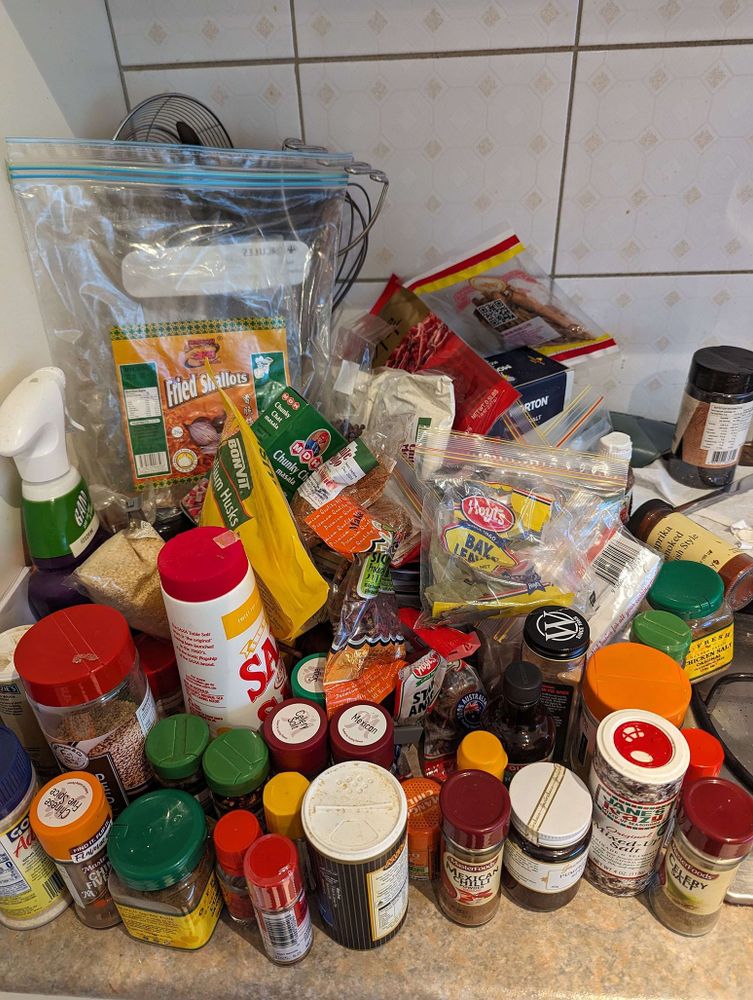 a countertop that is entirely covered with assorted spices, salts, dried herbs, etc. it's a disaster.