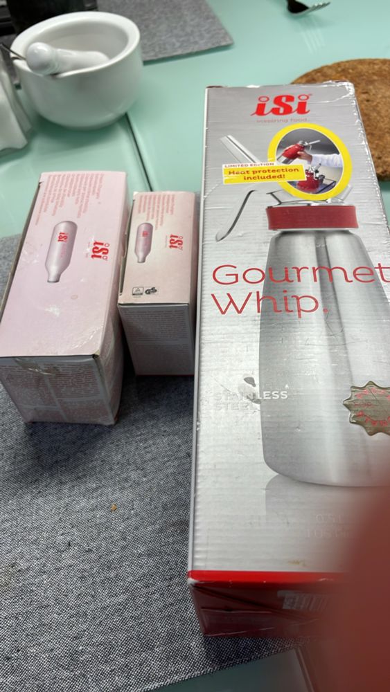 Eine Schachtel mit einem Sahne Spender einer bekannten Marke und 2 Schachteln mit den passenden Kartuschen 