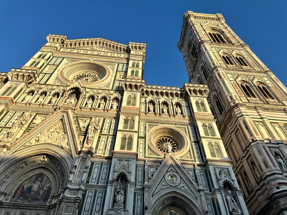 Ornate tricolored marble facade of a cathedral, looking up at the central tower and the bell tower to the right 