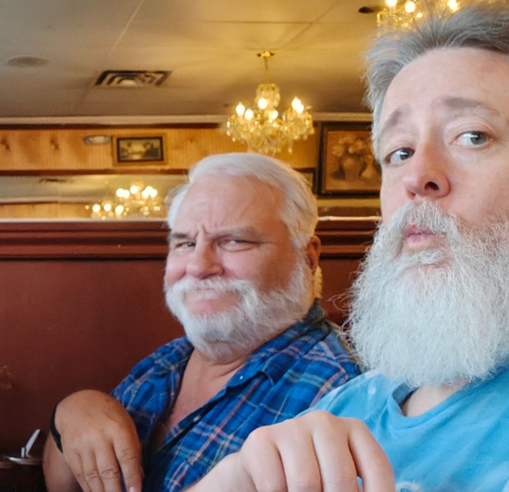 Two bearded men mug for a photo at a restaurant.