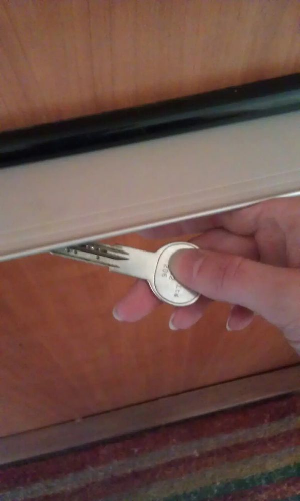 A hand holding a key that's halfway placed into an external letterbox 