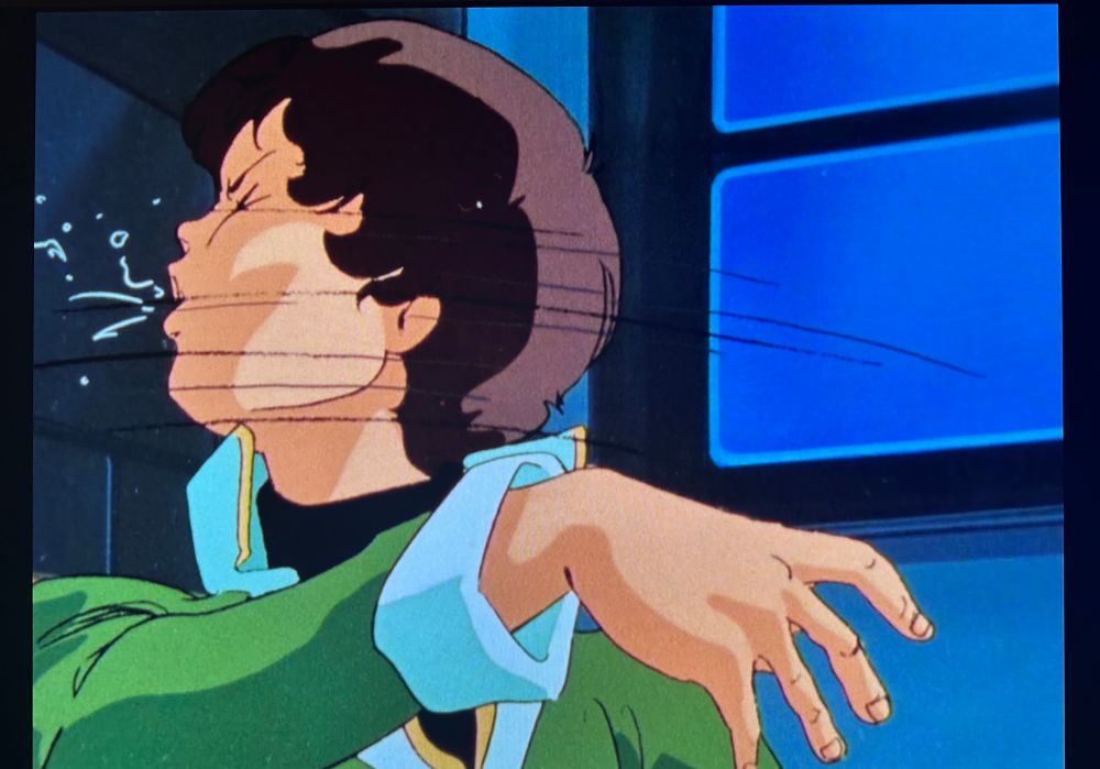 The aftermath of the previous shot. A young boy in a uniform (Katz, another Gundam child soldier/pilot) recoils to the frame-left with speed lines and spittle indicating he has just been slapped in the face