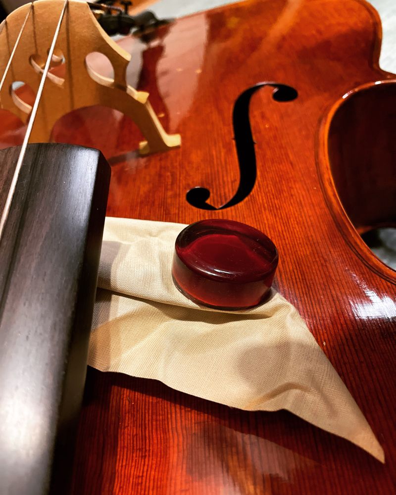 Clear amber-colored rosin (brand new) sitting on top of a cello lying on the fort floor.
