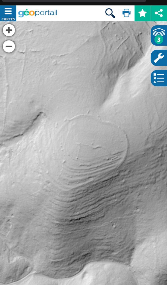 Un relief en plateau en gris clair, surplombant un vallon.
Une grande enceinte vaguement circulaire entoure ce promontoire.