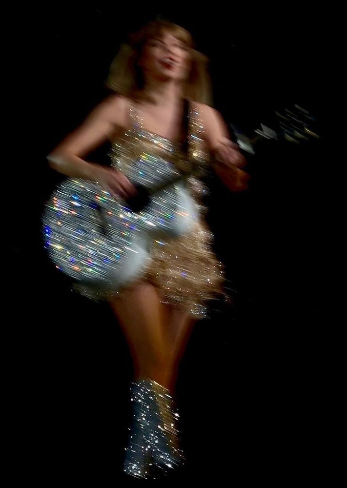 A photo of taylor swift on stage at the eras tour during fearless era, she's playing the guitar