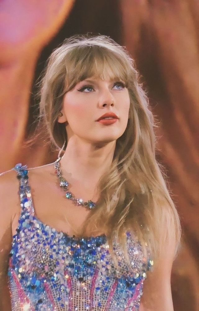 Taylor swift on stage at the eras tour wearing the blue and pink lover bodysuit