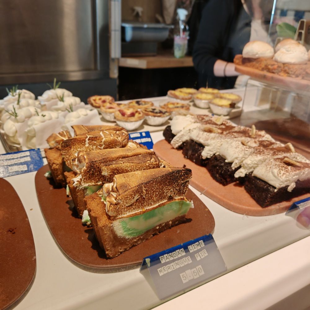 A display of cakes in a cafe, including a pandan lime meringue pie. 