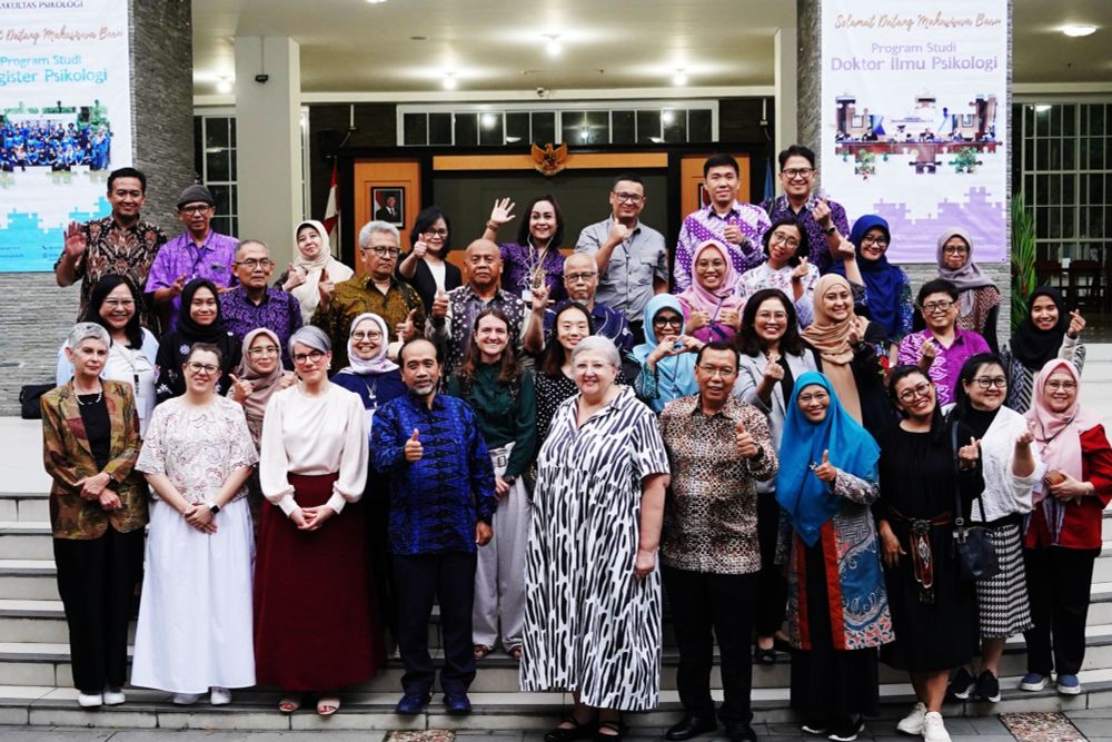 A large group of people from JBI and locals based in Indonesia pose on steps, smiling for the camera