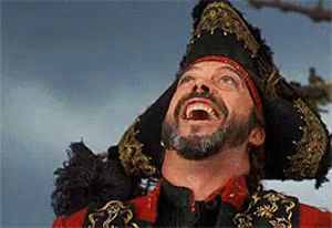 a man with a beard is wearing a pirate hat and smiling .