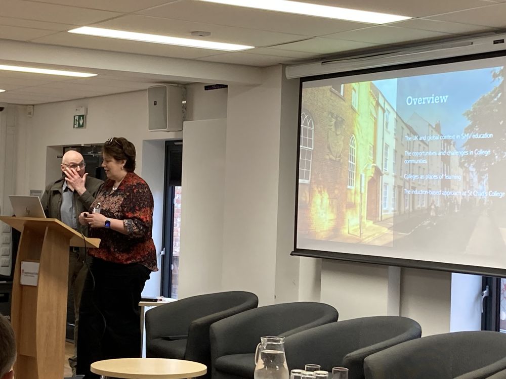 Dr Victoria Brown and Prof Graham Towl stand at a podium before an overview slide of their presentation.