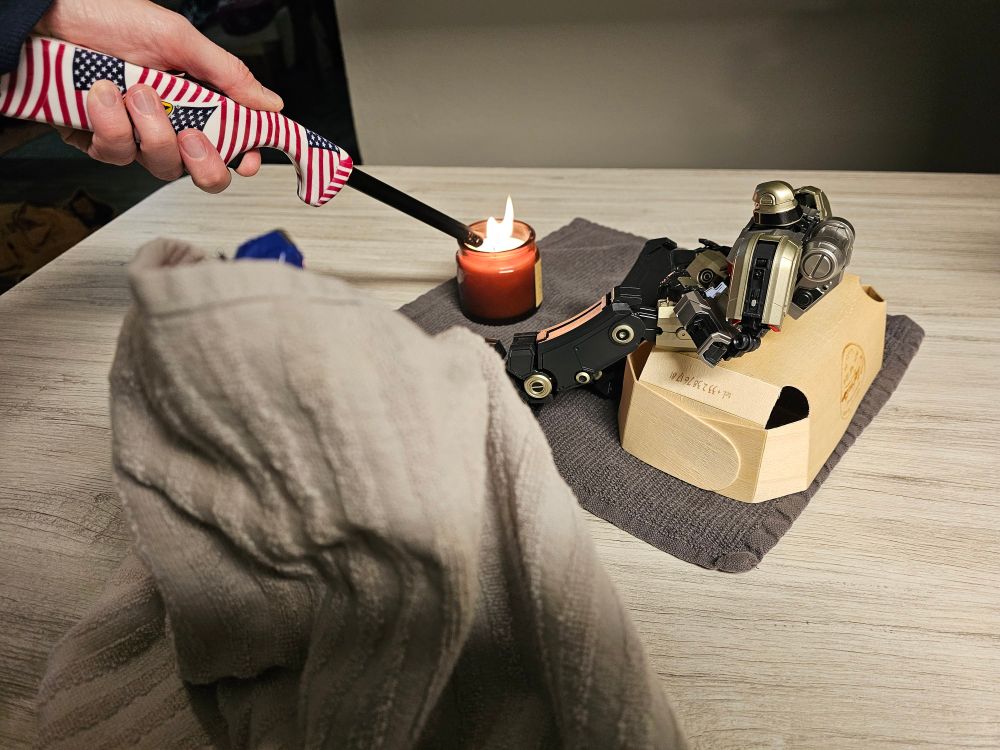 D16 sitting on a box watching a candle get lit. Orion is standing still wearing a towel like a blanket
