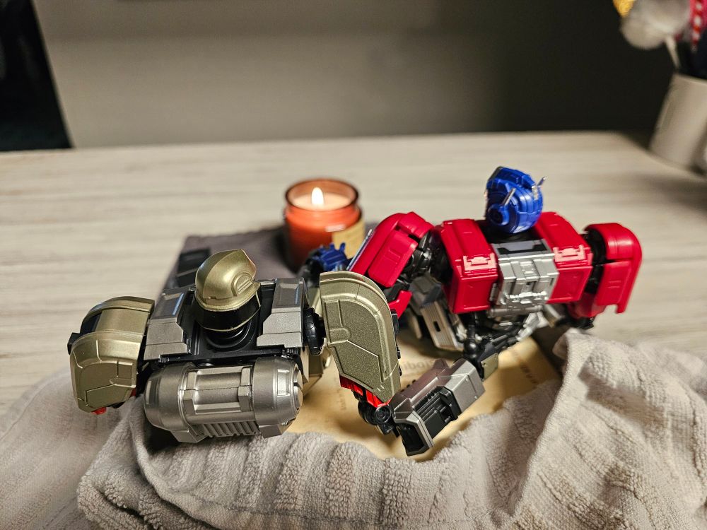 Orion and D16 sitting together by the candle. D16 has a hand at the small of Orion's back