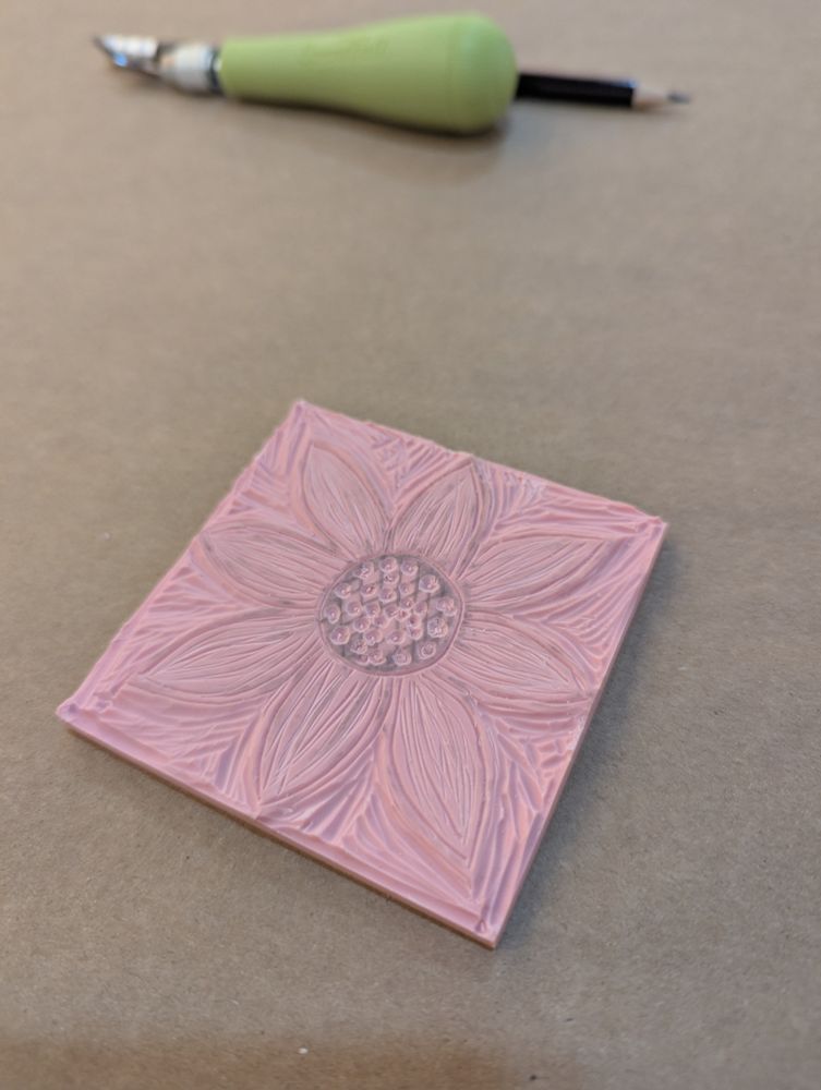 A pink rubber pad with a relief carving of something approaching a sunflower 