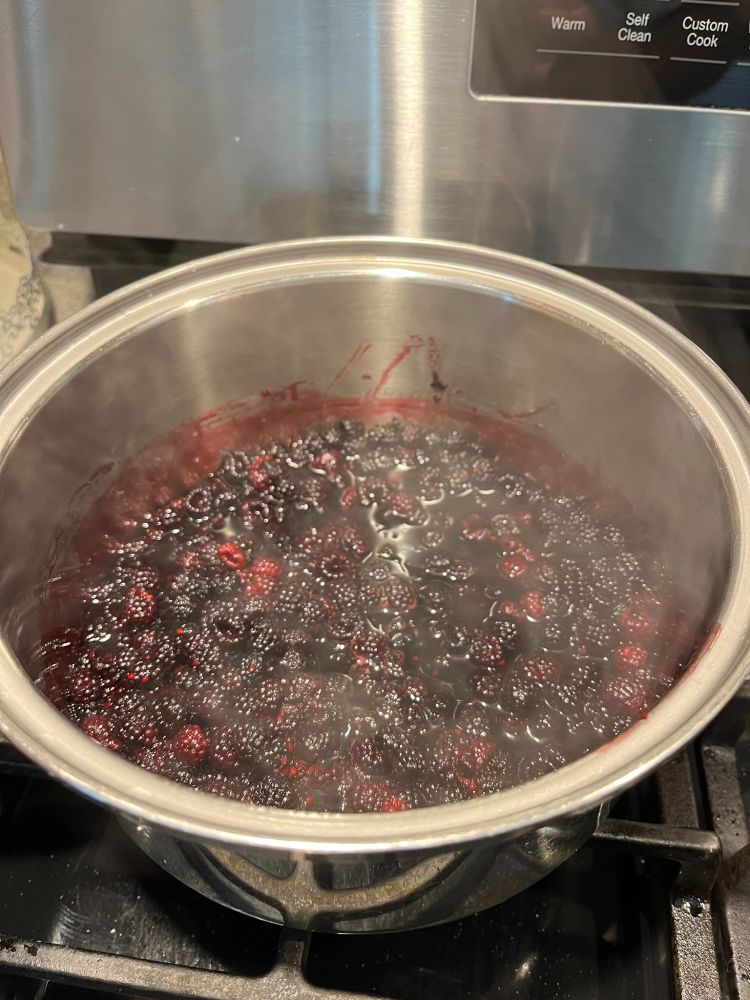 Black raspberries in a pot on the stove reducing to make a delicious sauce
