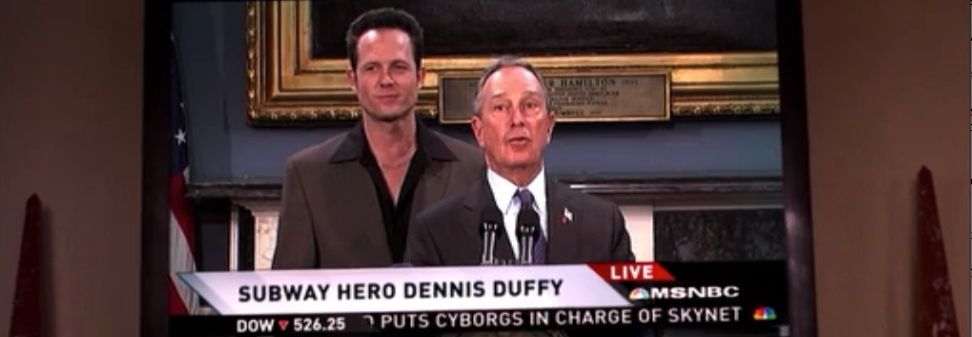 A still from the show 30 Rock: Dennis Duffy (Dean Winters), a smug white man with entirely too many buttons undone and too much chest exposed and another man who is ostensibly his lawyer & spokesman stand behind a podium. The chyron reads "SUBWAY HERO DENNIS DUFFY"