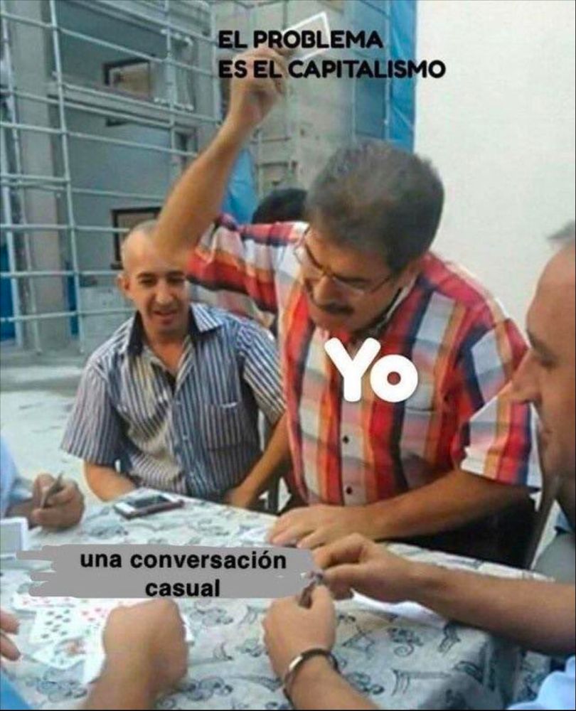 A man standing and getting ready to slam a playing card down on the table among other men playing cards. Captions in Spanish translate as follows: the man is labeled "me;" the table is "a casual conversation;" and the card is labeled "the problem is capitalism." 