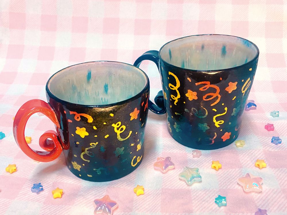 Both mugs with the handles on the left side now so we can see the reversed shape of the confetti swirl.
