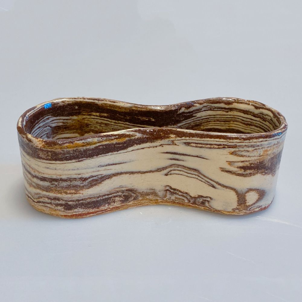 Marbled brown and white clay dish in a peanut shape
