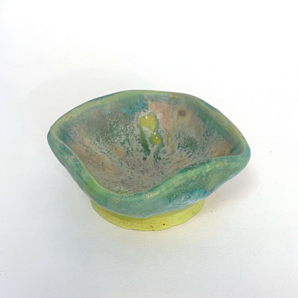Small rounded square cup or bowl. The glaze is drippy and speckled with teal, green, and tan areas. The foot is lime green.