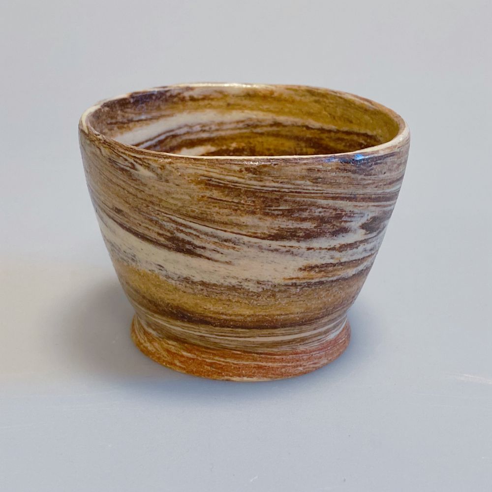 Marbled brown and white clay cup against a white background