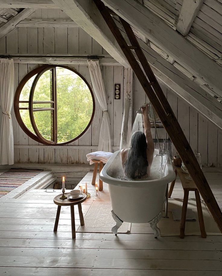 New Orleans house attic vintage whitewash wood floor bath tub round custom window ladder curtains candles table peace hardware faucet shower vintage beautiful room peaceful space solitary meditaation relaxation beeautiful inspiration design aspirational timeless beauty towels bubbles memorable moment